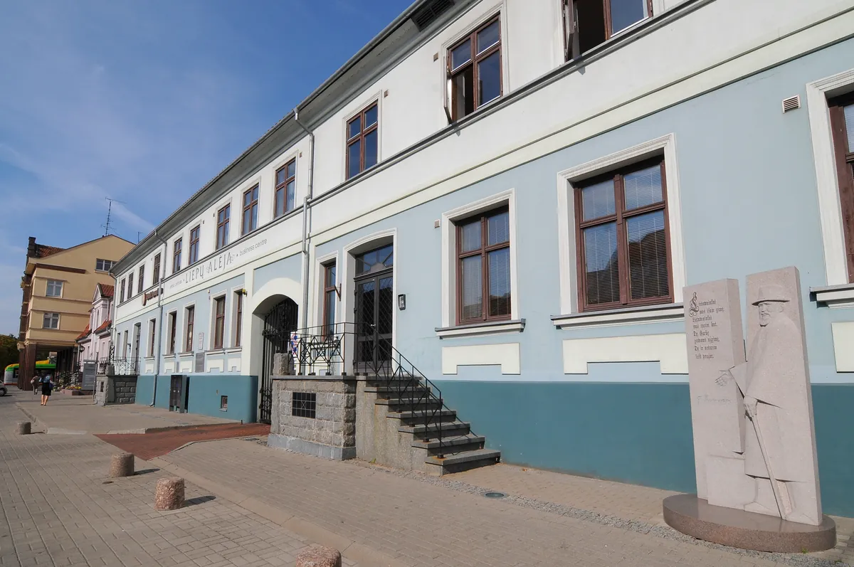 Liepų g. 5 pastatas: šviesiai mėlynas ir baltas fasadas, laiptai prie pagrindinio įėjimo, giedras dangus