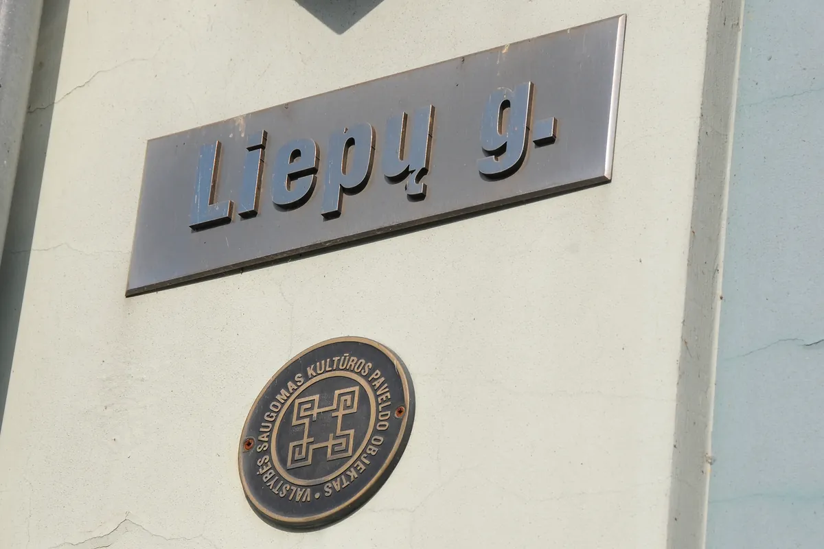 Gatvės lentelė „Liepų g.“ ir apskritas ženklas ant pastato sienos